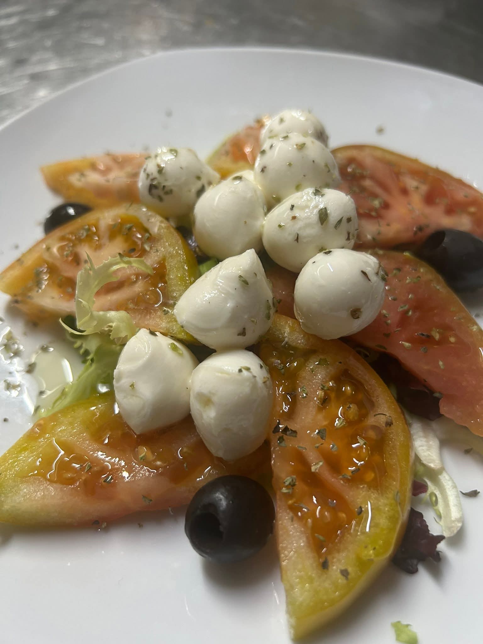 Ensalada de tomate con perlas de mozzarella y aceitunas